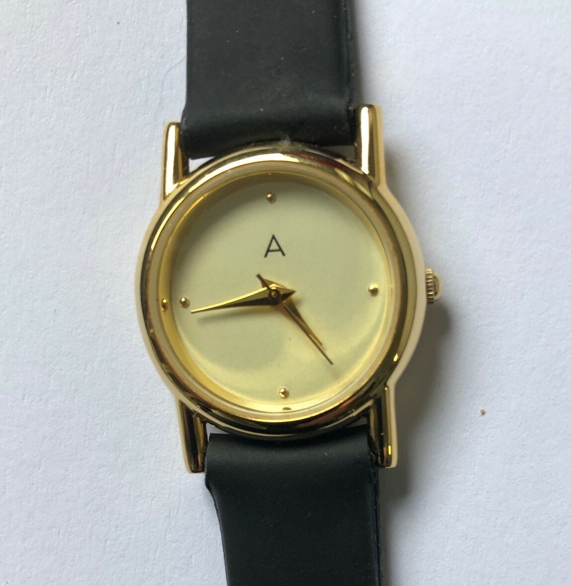 Ladies Avon 101 gold tone dress watch,ivory face,gold hands,black strap.