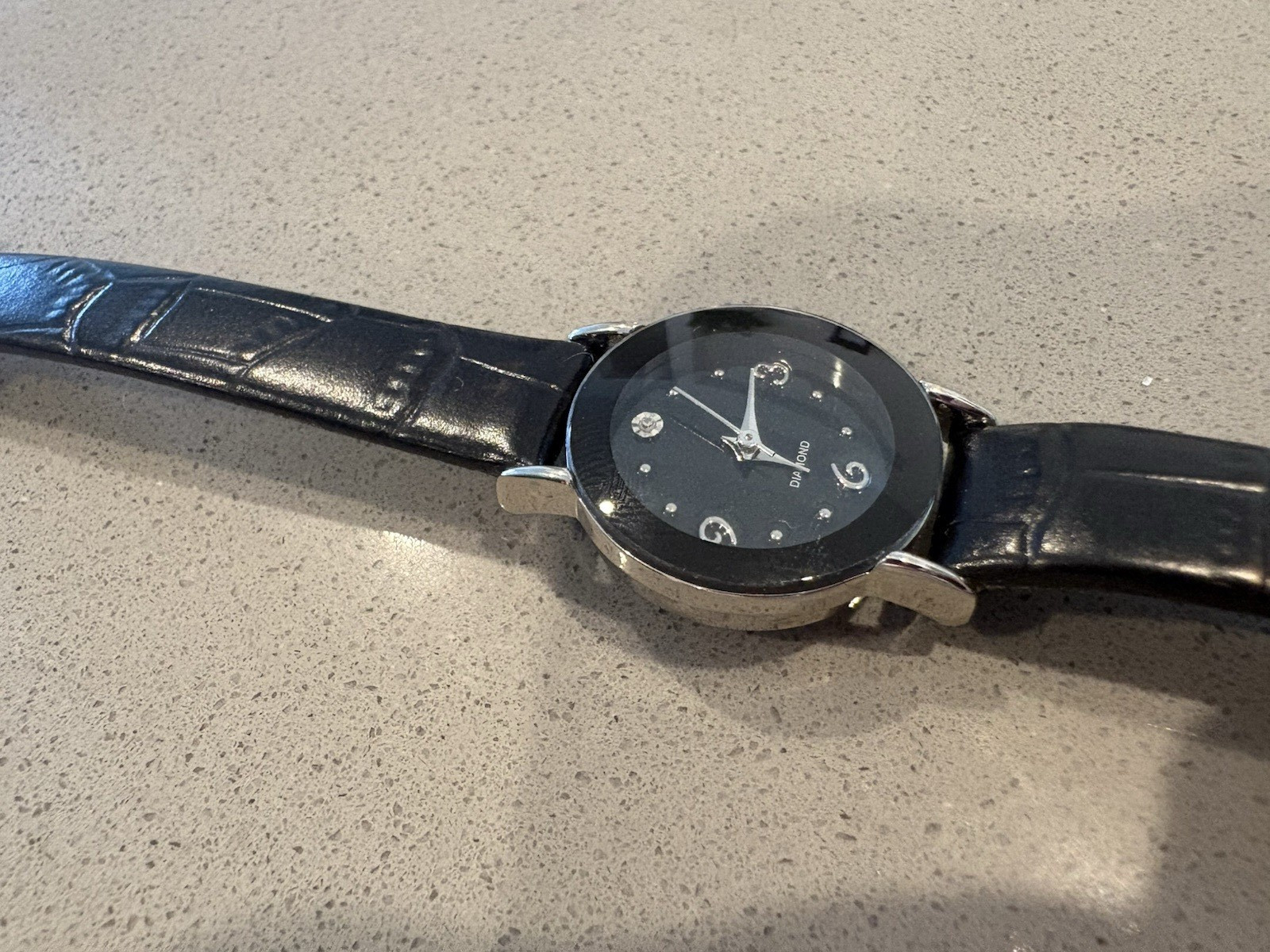 Avon watch featuring a genuine diamond accent on a black leather strap.