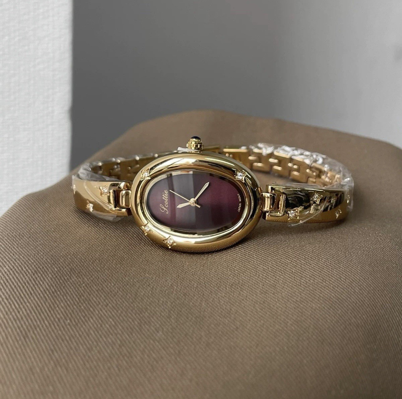 Elegant Gold Oval Ladies Luxury Watch with Dark Brown Maroon Dial & Star Accents