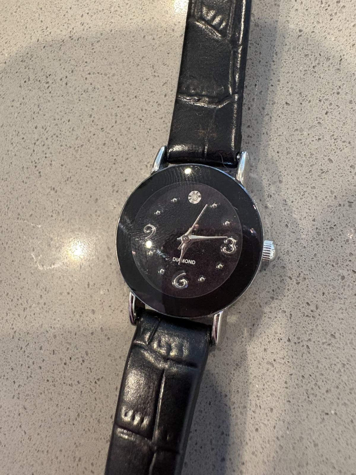 Avon watch featuring a genuine diamond accent on a black leather strap.