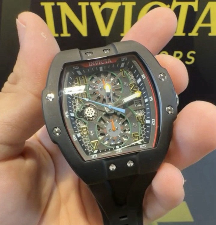 The Invicta 48027 men’s wristwatch features a striking black bezel and case