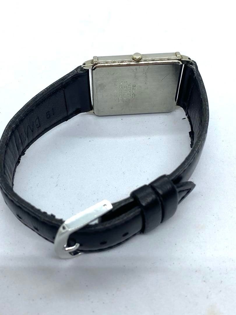 SEIKO rectangular quartz watch with black leather strap.